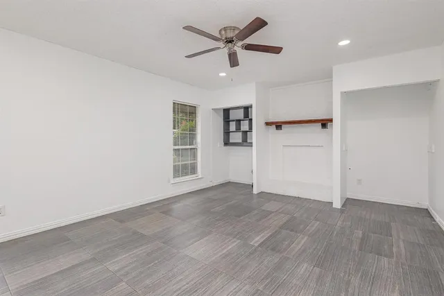 an empty room with wooden floor a ceiling fan and windows