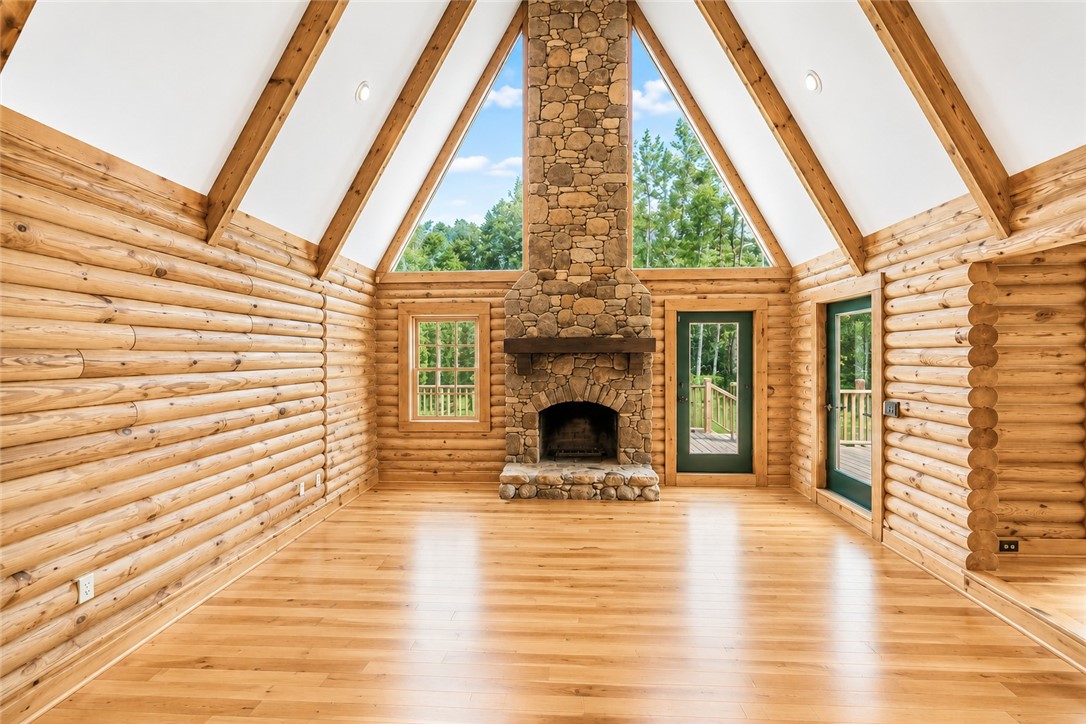 414 Devon Way Anderson, SC 29621 - Photo 5 of 50 A spacious log cabin great room, with a tall stone fireplace, hardwood floors, and abundant natural light from large windows.