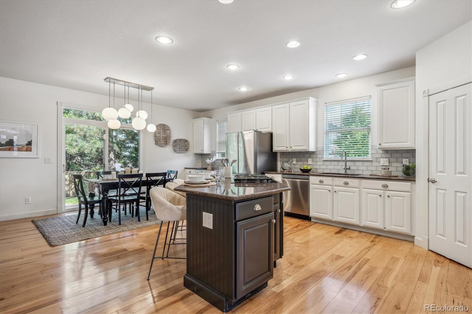 3319 Lynwood Avenue Highlands Ranch, CO 80126 - Photo 7 of 46 a kitchen with kitchen island granite countertop wooden floors and stainless steel appliances