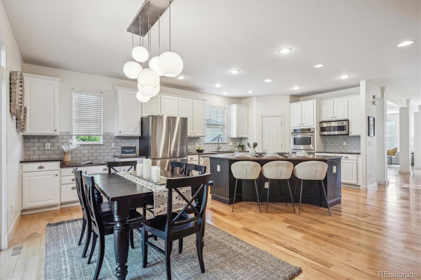 3319 Lynwood Avenue Highlands Ranch, CO 80126 - Photo 10 of 46 a kitchen with stainless steel appliances kitchen island granite countertop a dining table chairs stove a refrigerator and cabinets