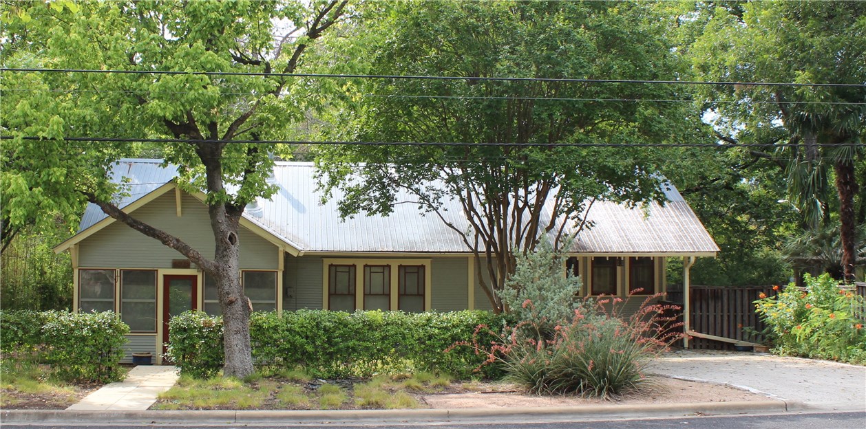 a front view of a house with a yard and potted plants