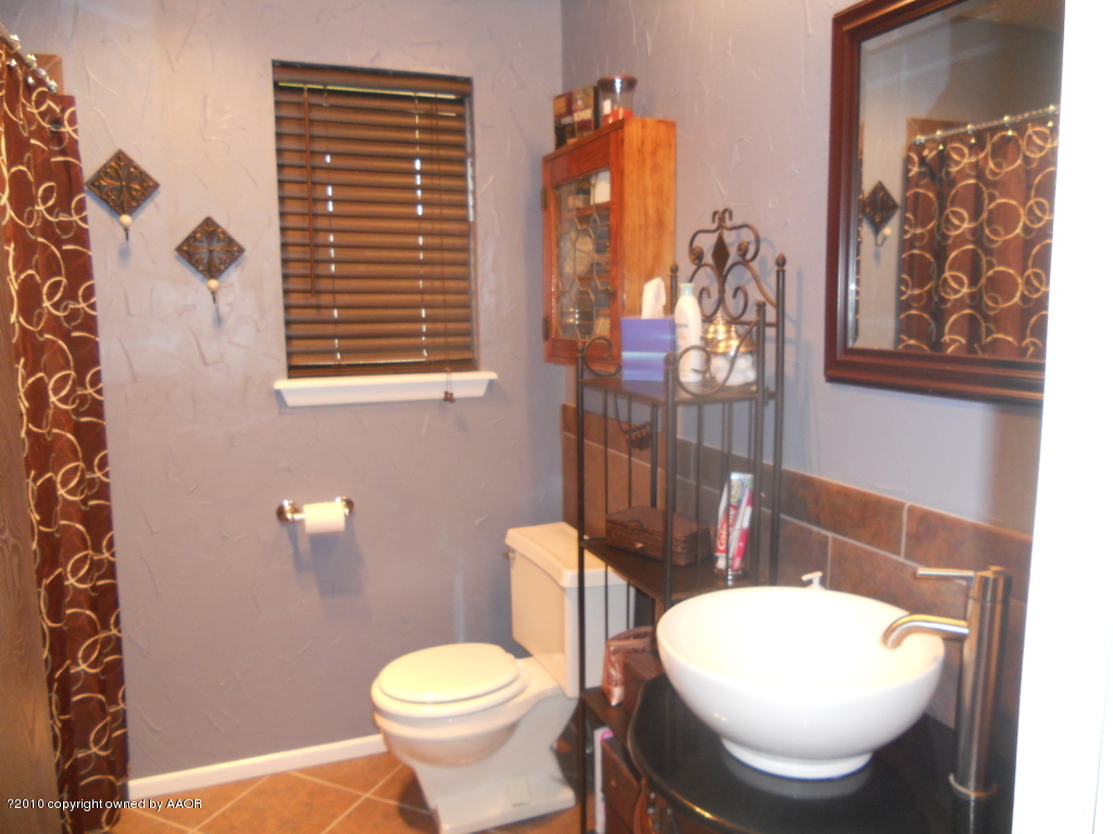 5117 McCarty Boulevard Amarillo, TX 79110 - Photo 13 of 17 a bathroom with a toilet a sink and a mirror