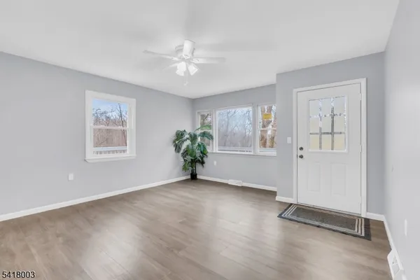 a view of an empty room with a window and wooden floor
