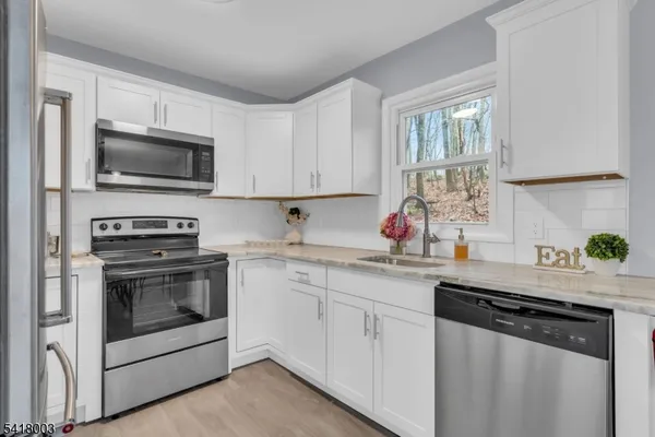 a kitchen with granite countertop a sink dishwasher stove and microwave with wooden floor