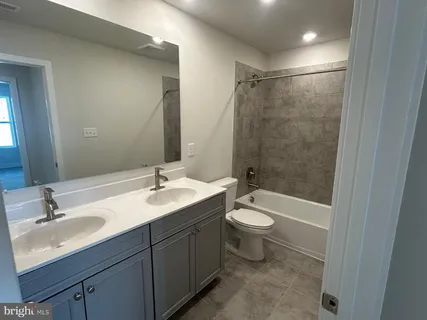 a bathroom with a double vanity sink toilet mirror and bathtub