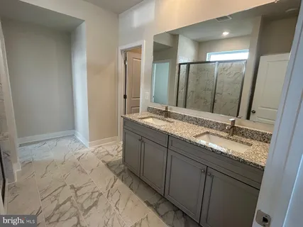a bathroom with double vanity and a mirror