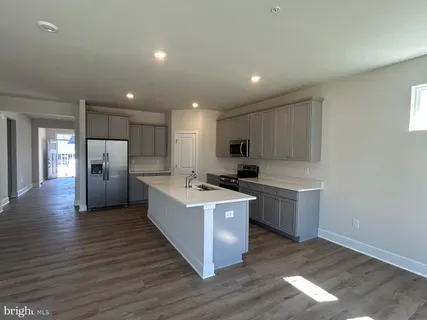 a kitchen with stainless steel appliances granite countertop a sink a microwave a refrigerator and white cabinets with wooden floor