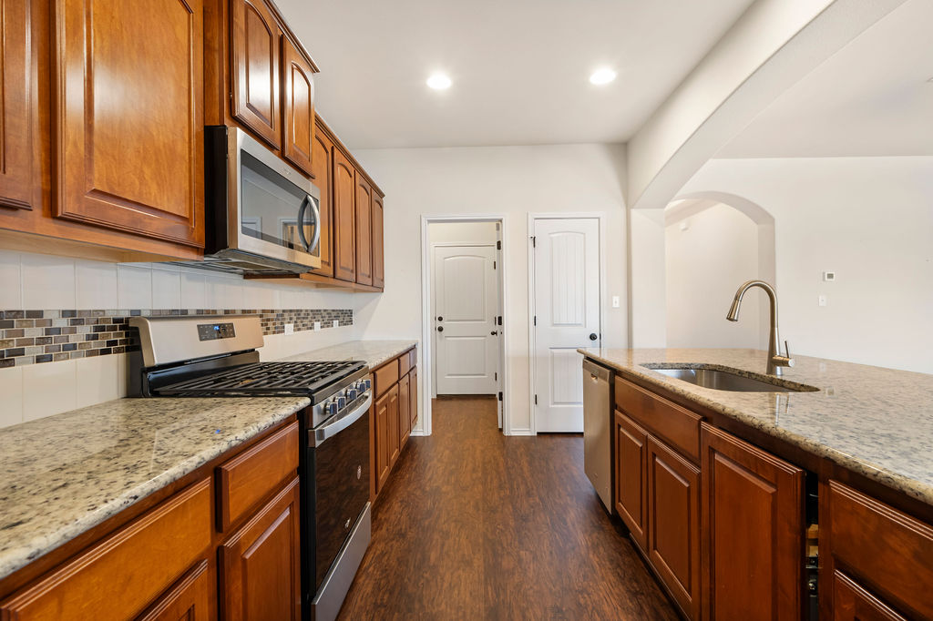 3473 Pauling Loop Round Rock, TX 78665 - Photo 13 of 33 a kitchen with stainless steel appliances granite countertop a sink a stove and a wooden floors