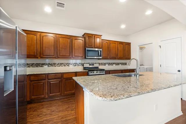 a kitchen with stainless steel appliances granite countertop a sink a stove and a wooden floors
