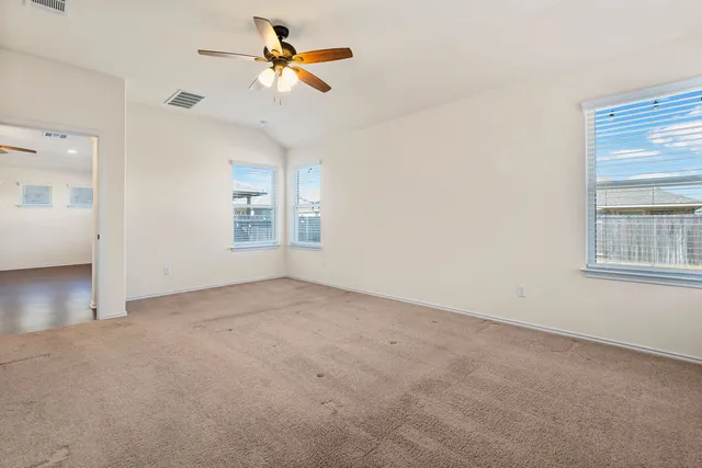 an empty room with windows and fan