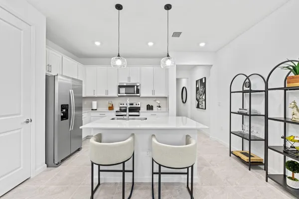 a kitchen with stainless steel appliances granite countertop a table chairs refrigerator and sink