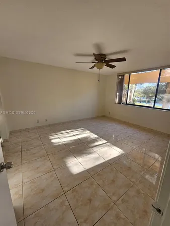en empty room with windows and ceiling fan