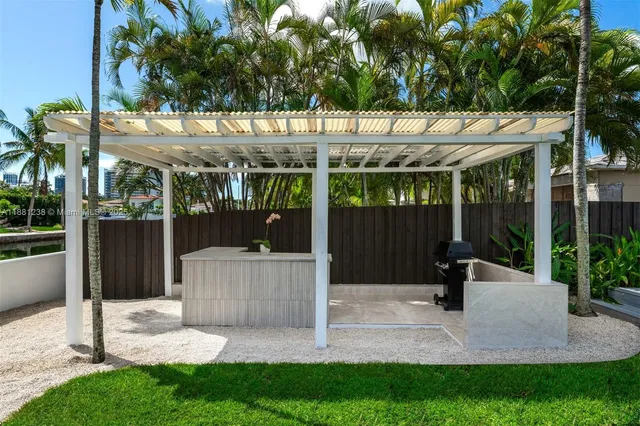 a view of a white house with a small yard and large tree