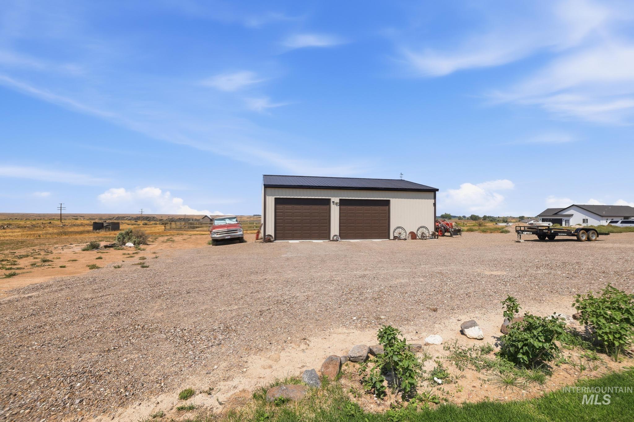 178 Syringa Loop Shoshone, ID 83352 - Photo 32 of 35 Detached two-car garage with a light-colored siding facade and dark brown overhead doors