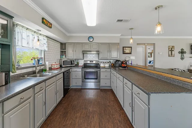 a kitchen with stainless steel appliances granite countertop a refrigerator a sink dishwasher a stove and white cabinets with wooden floor