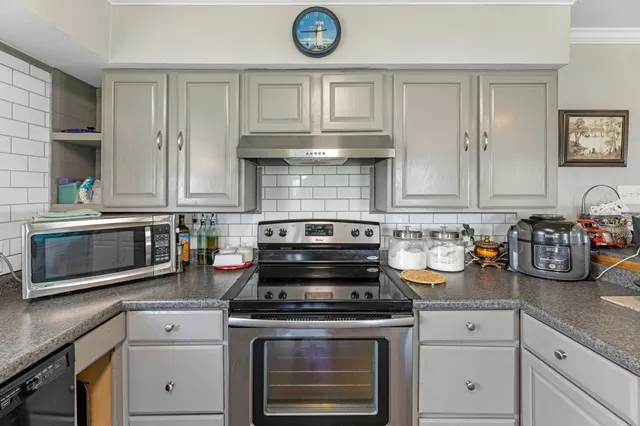 a kitchen with stainless steel appliances a sink dishwasher a stove top oven a refrigerator with wooden floors