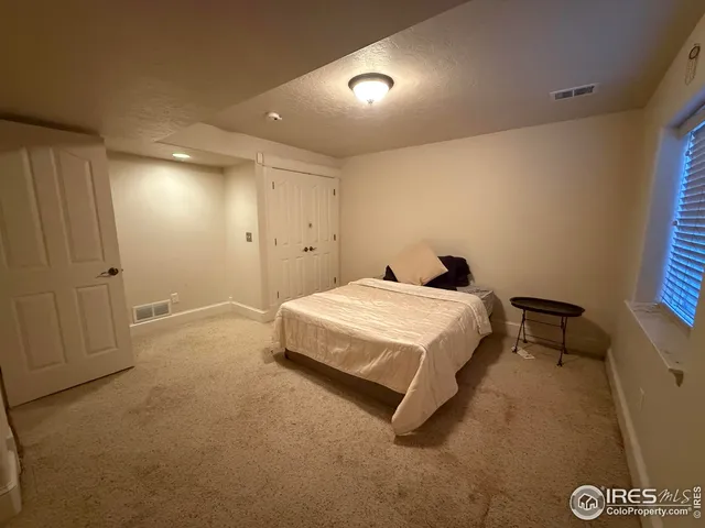 a spacious bedroom with a bed and a night stand
