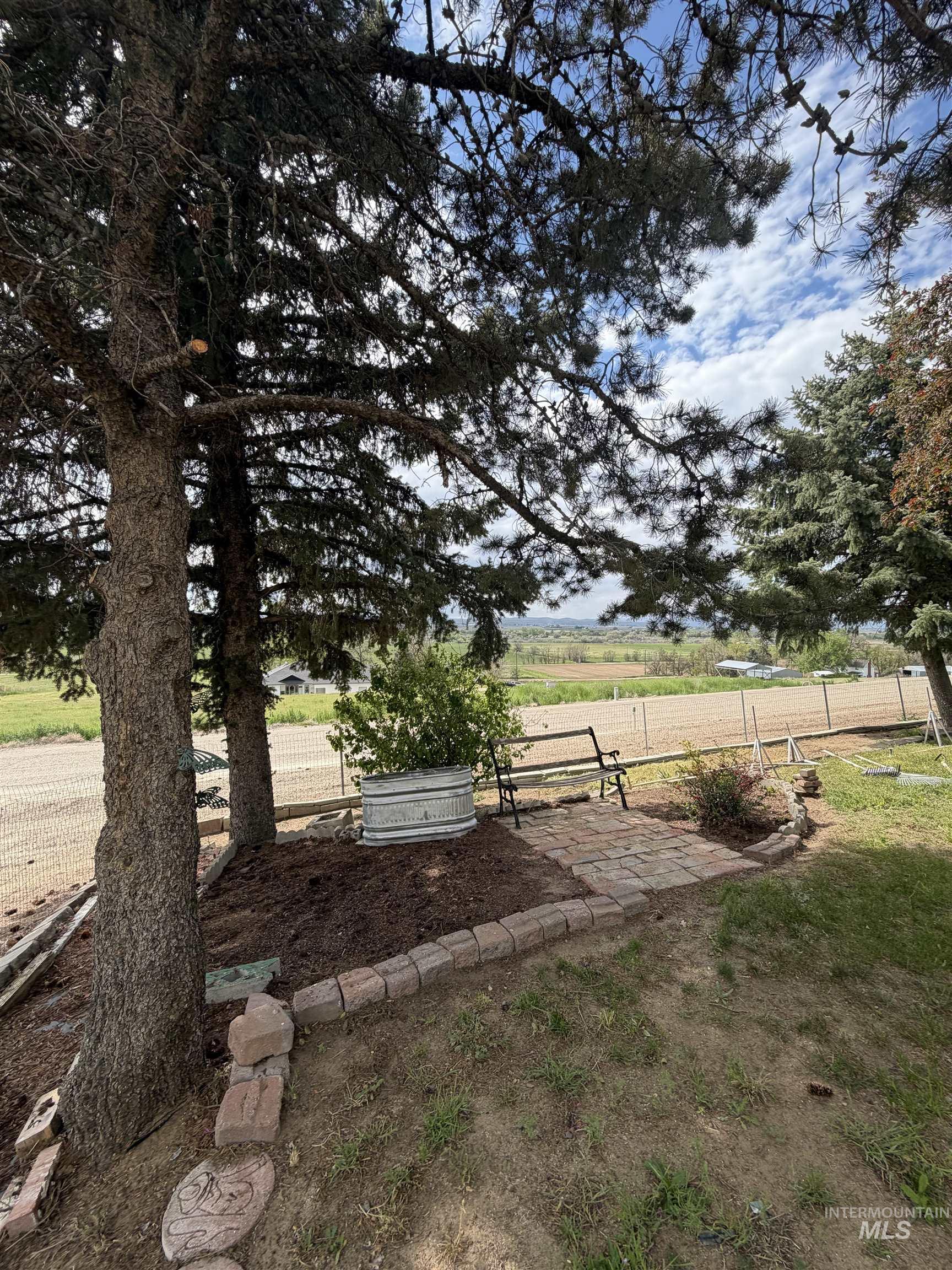 12184 Hill Road Payette, ID 83661 - Photo 35 of 35 Shaded outdoor patio area featuring a paver stone walkway, decorative stone border, and mature trees