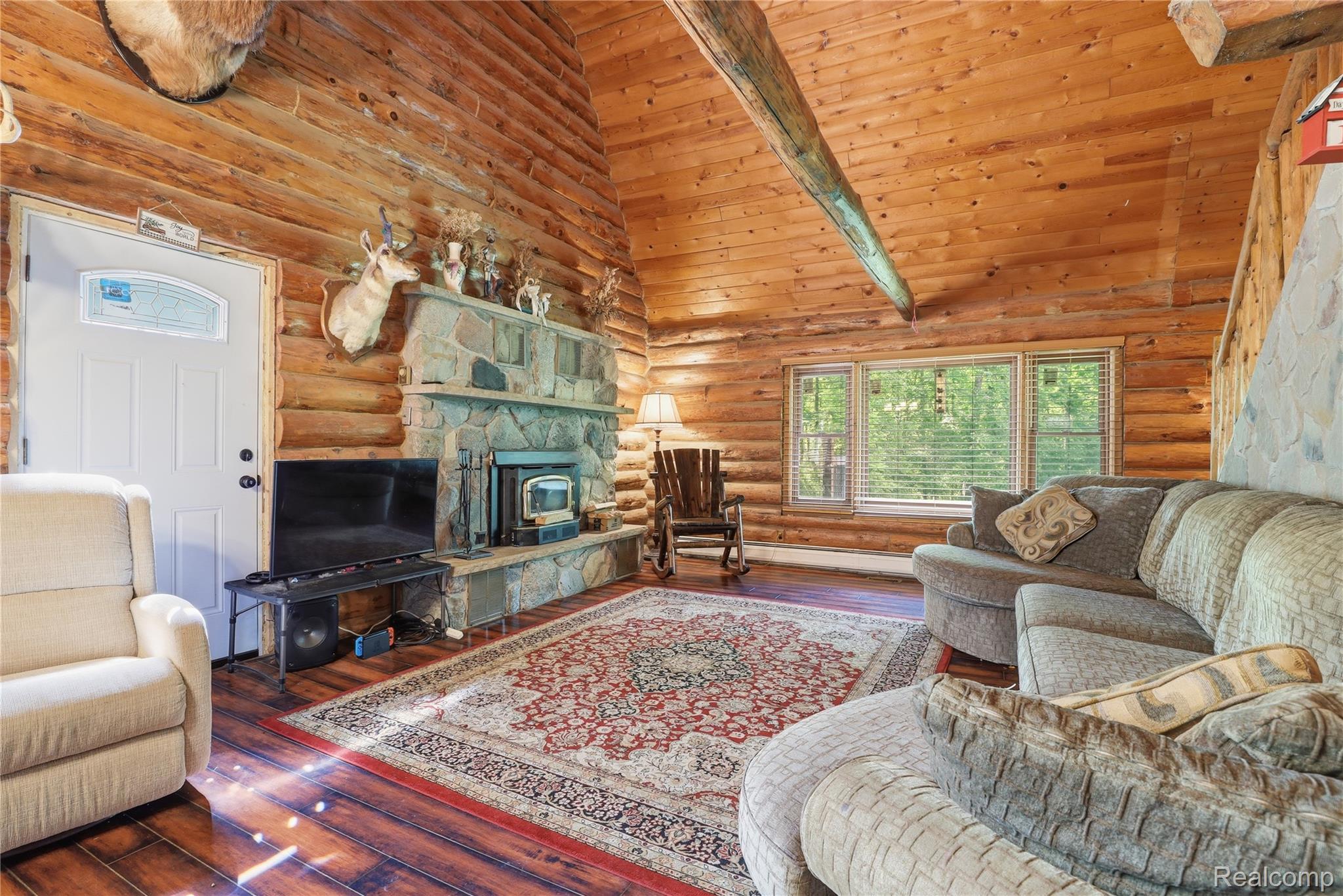 14830 Sheridan Road Byron, MI 48418 - Photo 9 of 74 Vaulted wood-paneled ceiling with exposed wood beam and full log walls