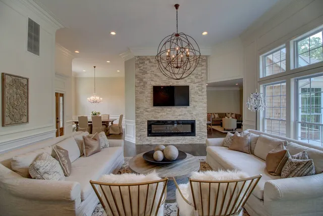 a living room with furniture a fireplace and a chandelier