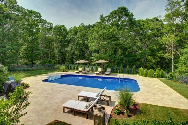 a view of a swimming pool with lawn chairs under an umbrella