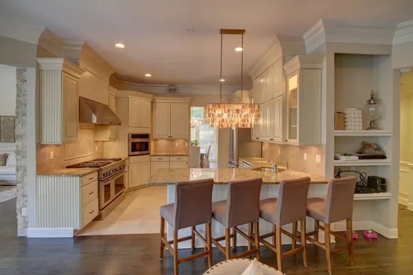 a kitchen with stainless steel appliances kitchen island granite countertop a table chairs stove and white cabinets
