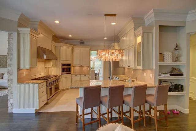 a kitchen with stainless steel appliances kitchen island granite countertop a table chairs stove and white cabinets