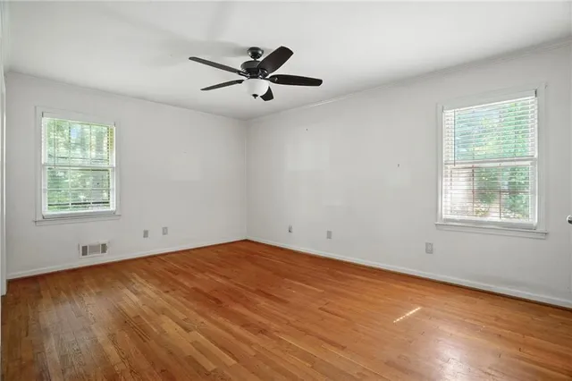 an empty room with wooden floor and windows