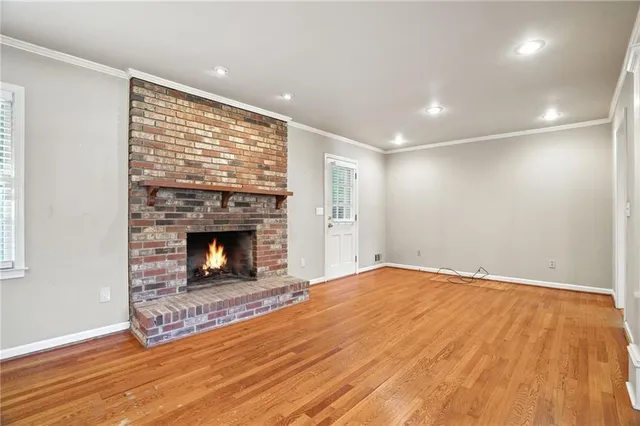 a view of an empty room with wooden floor fireplace and a window