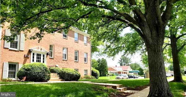 a view of a white house next to a yard with big trees