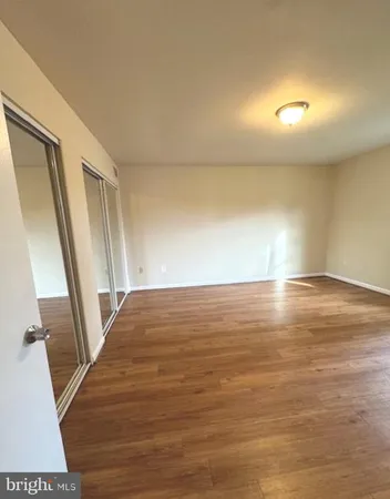 a view of an empty room with wooden floor and stairs