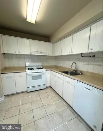 a kitchen with a sink a stove top oven and white cabinets