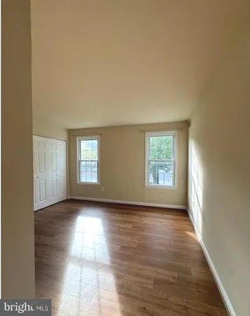 a view of an empty room with wooden floor and window