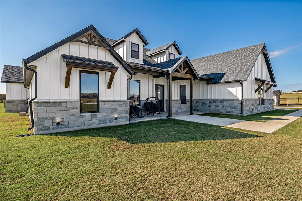 310 Runyan Rnch Road Tolar, TX 76476 - Photo 2 of 35 View of front of property with board and batten siding, a shingled roof, a front lawn, and stone siding