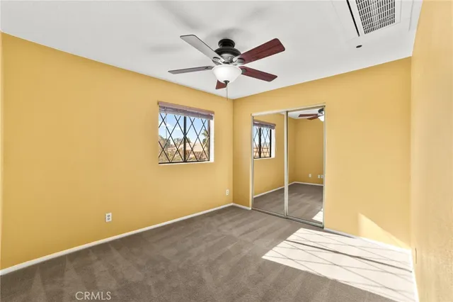 an empty room with ceiling fan and window