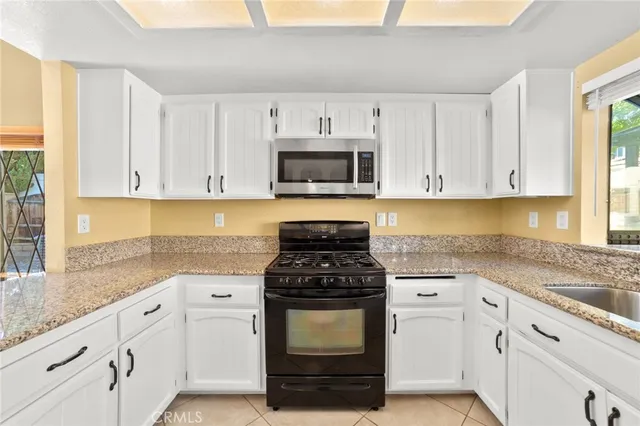 a kitchen with granite countertop white cabinets and stainless steel appliances