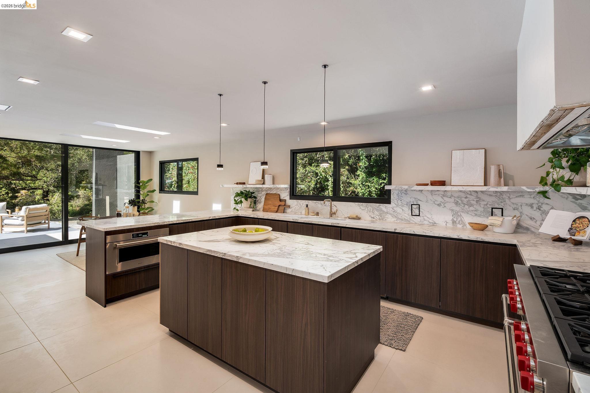 5645 Bacon Road Oakland, CA 94619 - Photo 26 of 60 Kitchen with a peninsula, stainless steel appliances, modern cabinets, dark wood finish cabinetry, and light stone counters