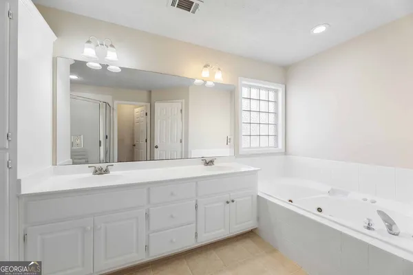 a bathroom with a tub a sink double vanity and a mirror