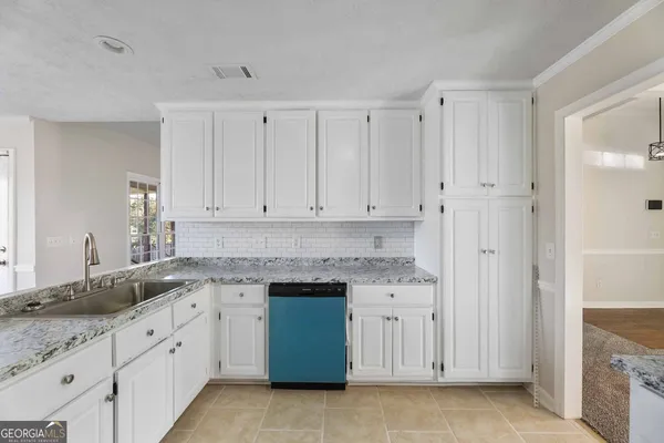 a kitchen with granite countertop white cabinets and sink