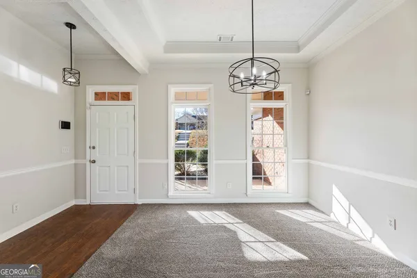 a view of a room with wooden floor chandeliers and kitchen view