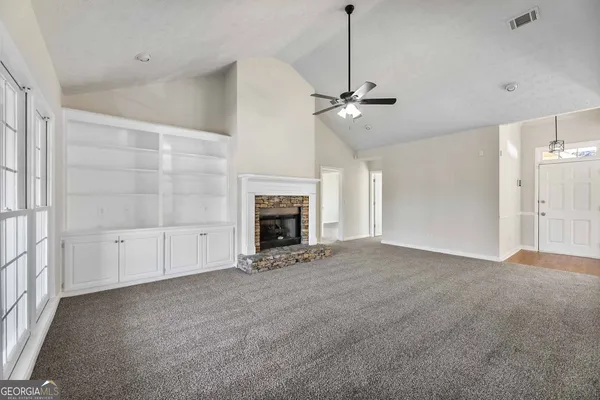 a view of an empty room with a fireplace and a window