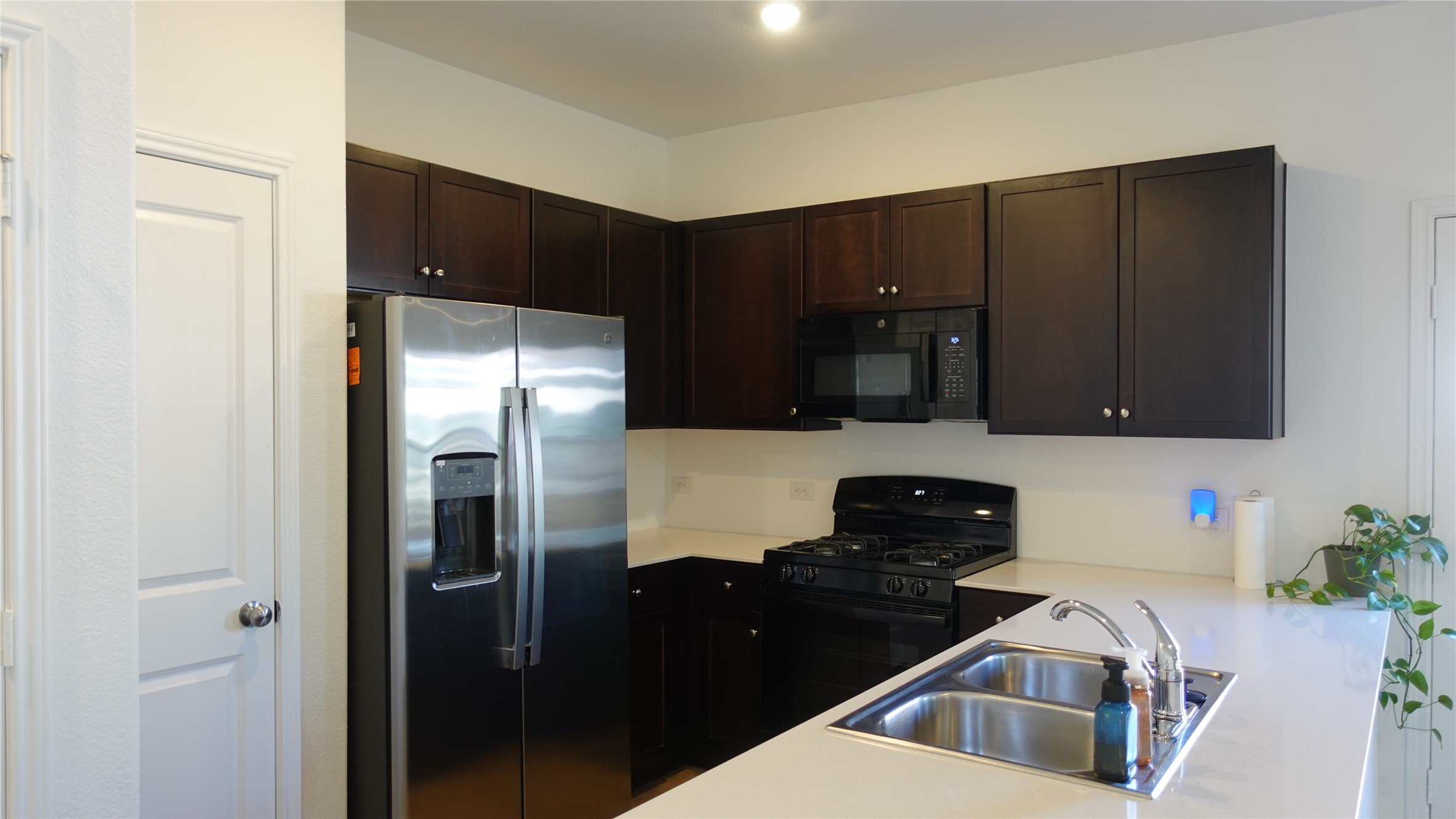 203 Tufted Duck Path Kyle, TX 78640 - Photo 5 of 19 Kitchen with black appliances, light countertops, and dark wood finish cabinetry