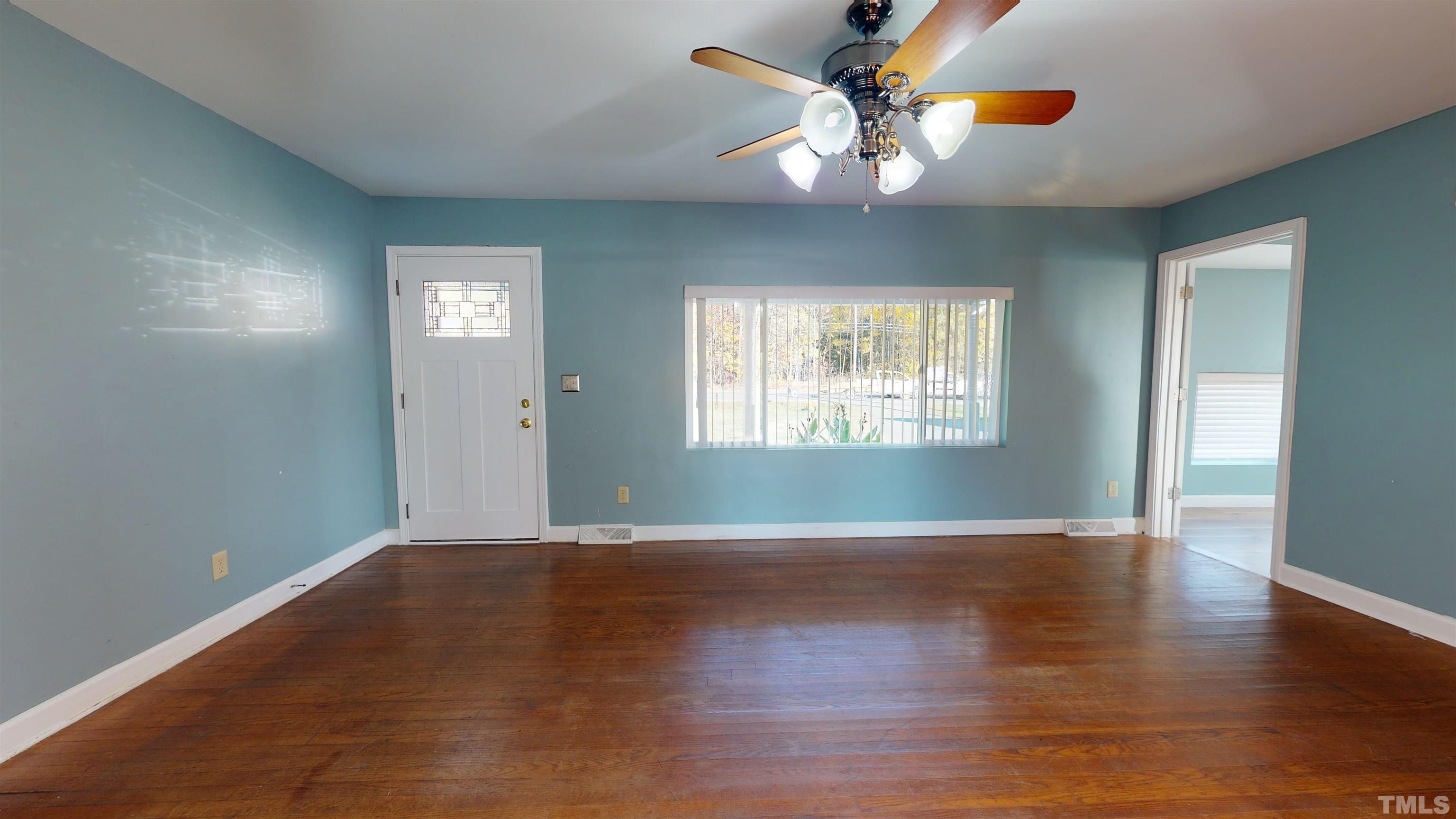 1306 Old Durham Road Roxboro, NC 27573 - Photo 11 of 28 an empty room with wooden floor chandelier fan and windows