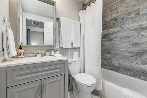 a bathroom with a granite countertop toilet sink and mirror