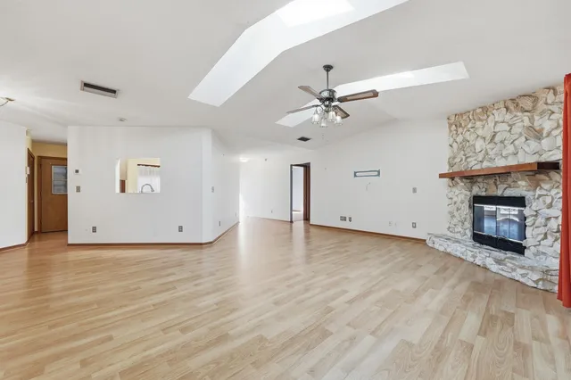 an empty room with a fireplace and chandelier fan