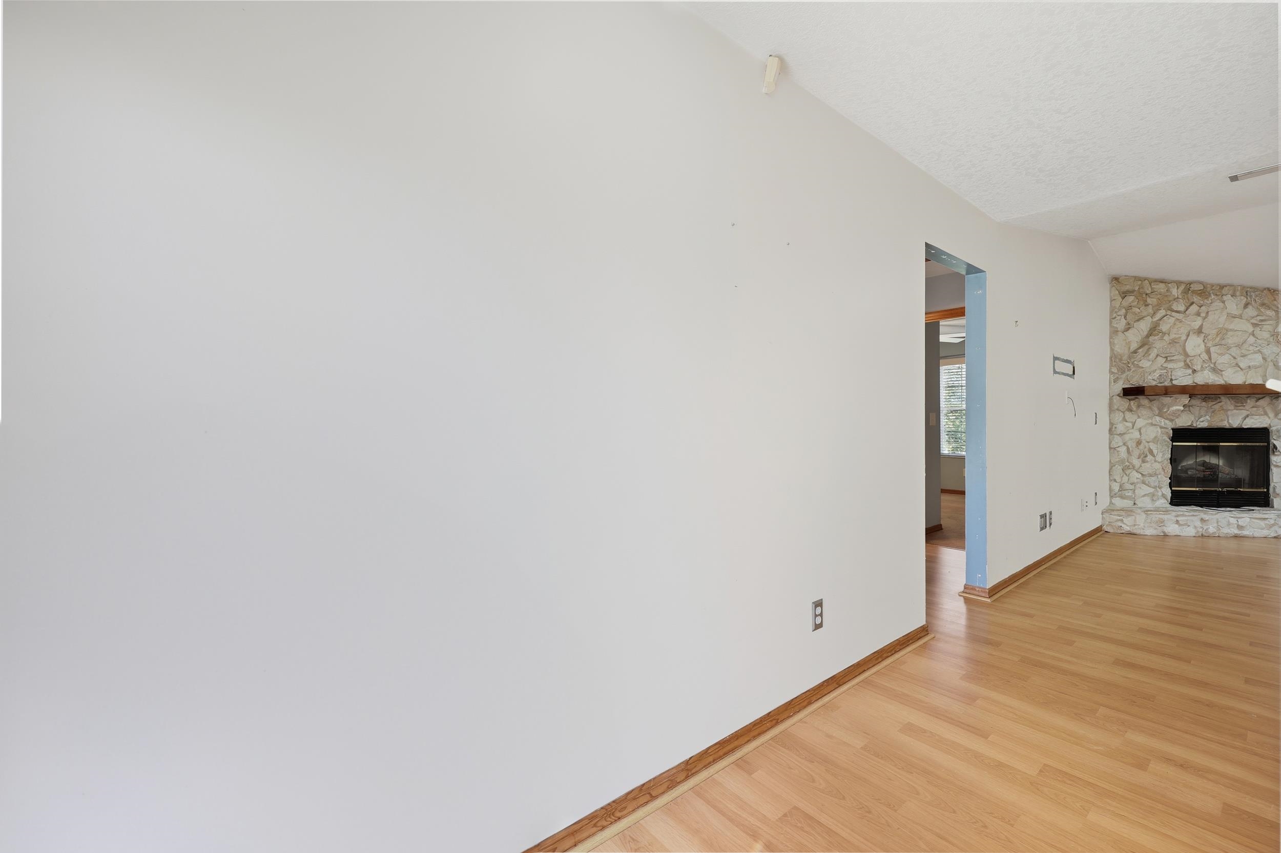 115 Segovia Road St. Augustine, FL 32086 - Photo 12 of 48 Unfurnished living room with light wood-style flooring, a textured ceiling, a stone fireplace, and vaulted ceiling