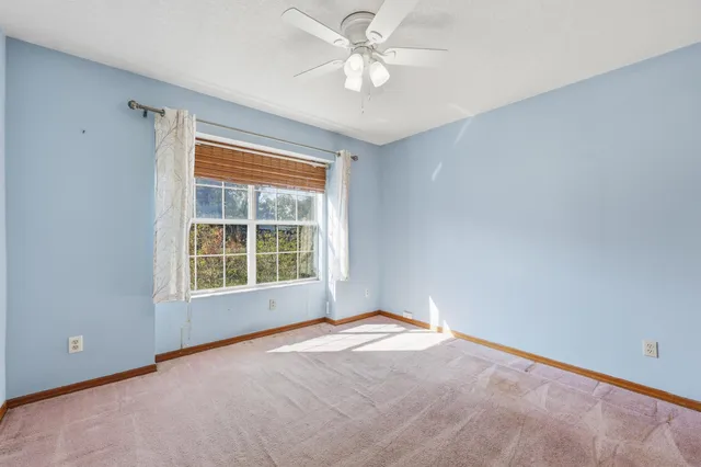 an empty room with a window and a fan