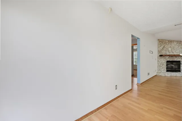 a view of empty room with wooden floor and fireplace
