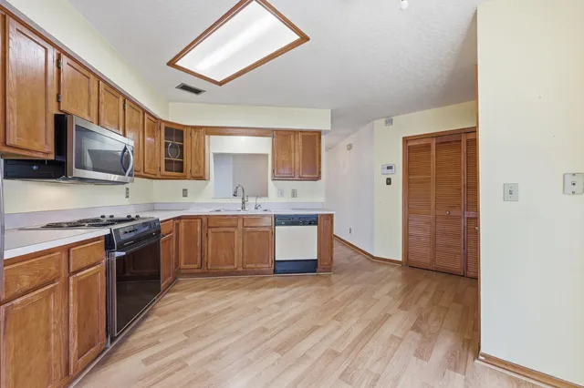 a large kitchen with stainless steel appliances granite countertop a stove a sink dishwasher and a microwave oven with wooden floor