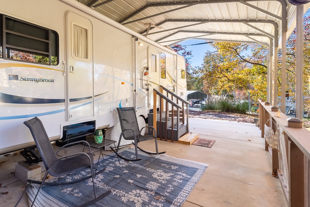 66-186 Peaceful Loop Chatsworth, GA 30705 - Photo 15 of 31 a view of a porch with couches table and chairs under an umbrella